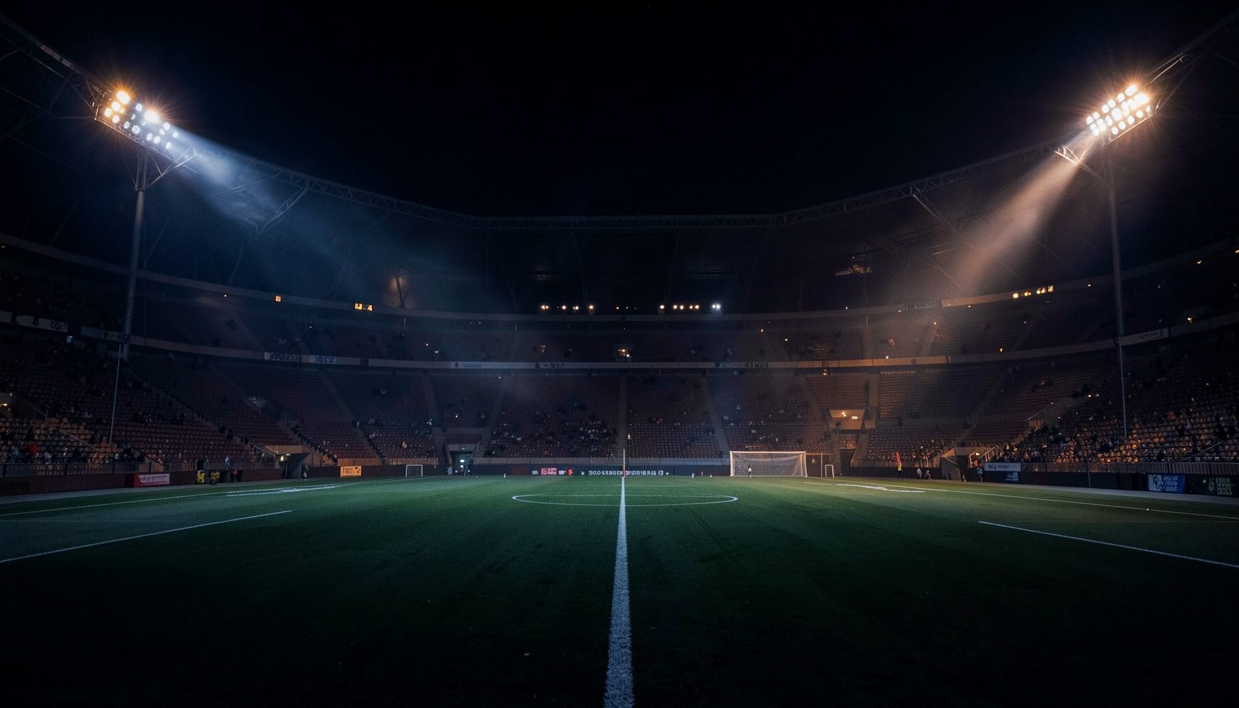 Dark atmospheric stadium at night with floodlights casting dramatic beams across the field in deep navy and charcoal tones